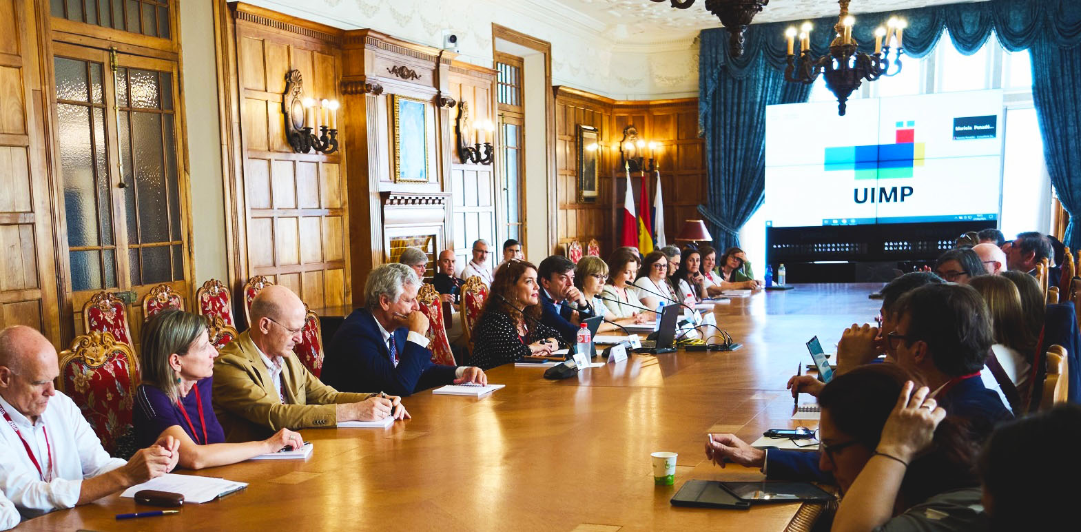 Imagen del primer día del curso, durante la apertura. Junto a parte de las personas asistentes, en el centro de la mesa y frente a los micrófonos, aparecen de izquierda a derecha la secretaria general de Investigación del Ministerio de Ciencia, Innovación y Universidades, Eva Ortega-Paíno​; el Rector de la UIMP, Carlos Andradas; la directora del ISCIII, Marina Pollán, y la subdirectora general de Evaluación y Fomento de la Investigación del Instituto, Pilar Gayoso (foto: UIMP)